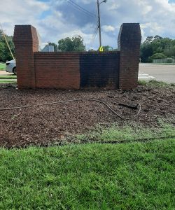 image of behind brick sign on grass in between power washing